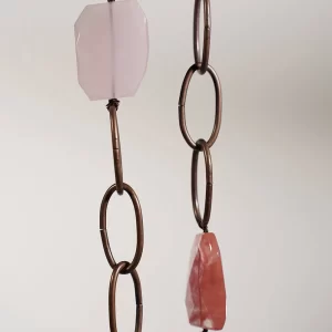 Un par de collares rosas y marrones que cuelgan de una cadena.