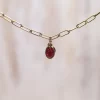 Un collar de cadena de oro con una piedra roja.