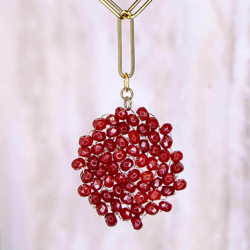 Un collar de cuentas rojas colgado de una cadena de oro.