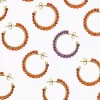 Un grupo de pendientes de aro de color naranja y morado sobre fondo blanco.