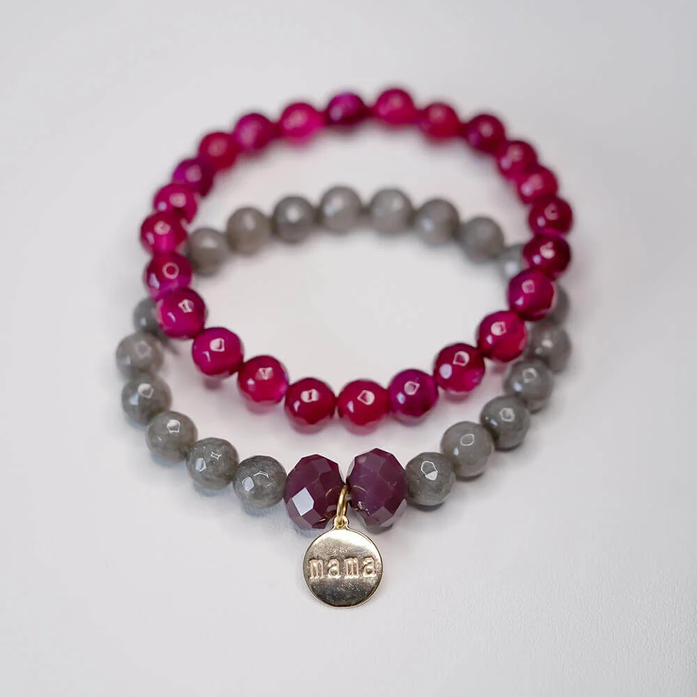 Un par de pulseras rosas y grises con un charm dorado.